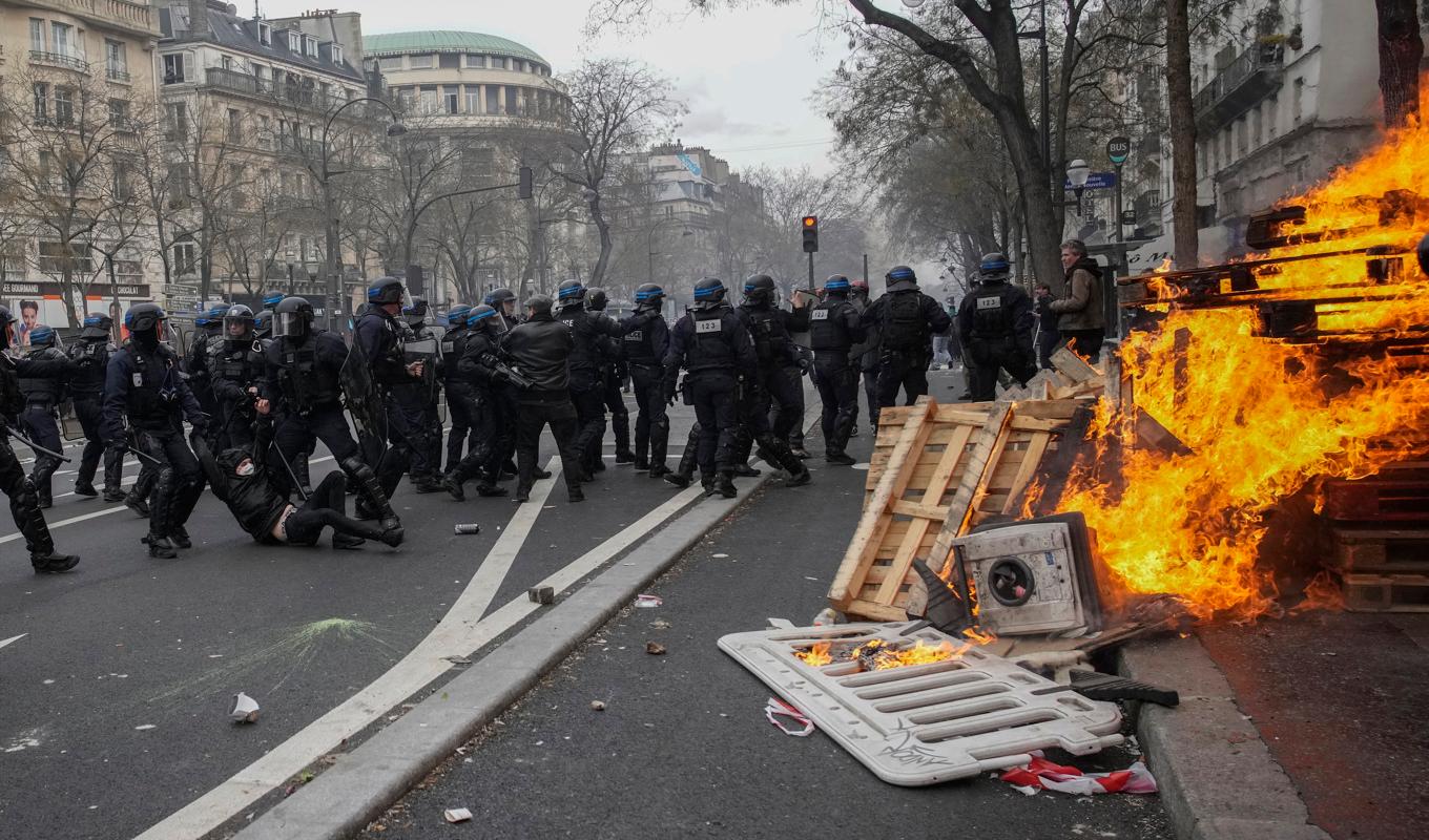 Kravallutrustad polis i sammandrabbning med demonstranter i Paris. Foto: Christophe Ena/AP/TT