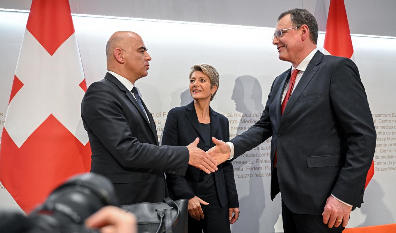 Schweiz president Alain Berset skakar hand med SNB:s ordförande Thomas Jordan, med Schweiz finansminister Karin Keller-Sutter i bakgrunden. Foto: Fabrice Coffrini/AFP via Getty Images